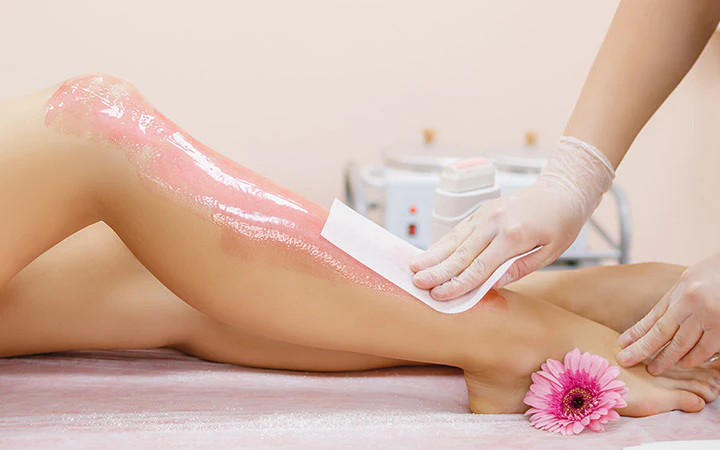 Applying wax to a young woman s leg for hair